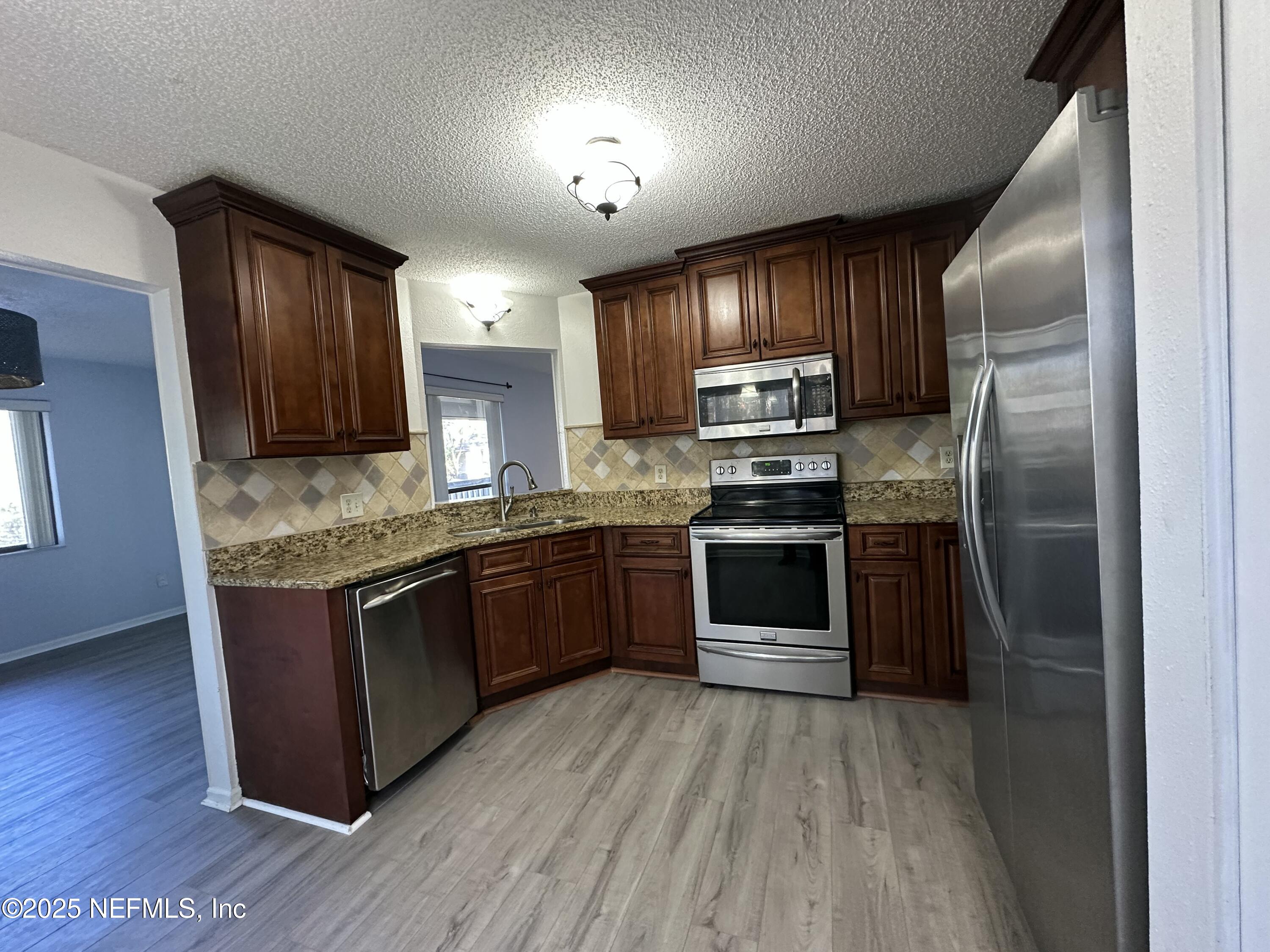 3801 Crown Point Road, Unit 3082 Jacksonville, FL 32257 - Photo 15 of 41 a kitchen with granite countertop wooden floors stainless steel appliances and a counter space