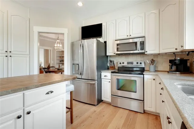 a kitchen with white cabinets and stainless steel appliances