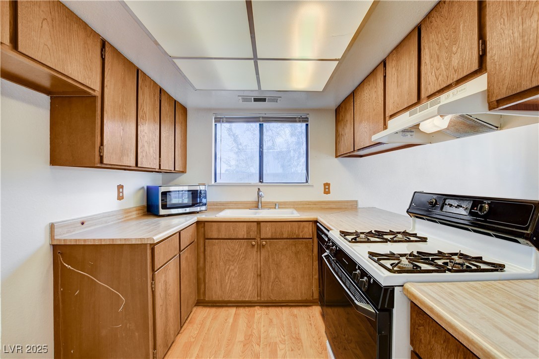 511 Chelsea Drive Henderson, NV 89014 - Photo 9 of 21 Kitchen with gas range, light wood-style floors, and brown cabinetry