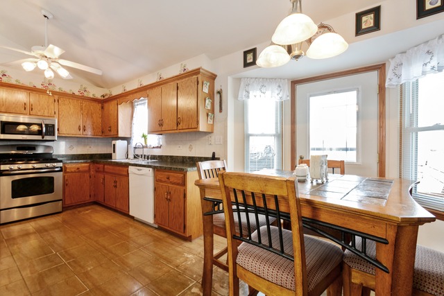 334 Highland Road Matteson, IL 60443 - Photo 4 of 10 a kitchen with stainless steel appliances granite countertop a stove a sink dishwasher a dining table and chairs with wooden floor