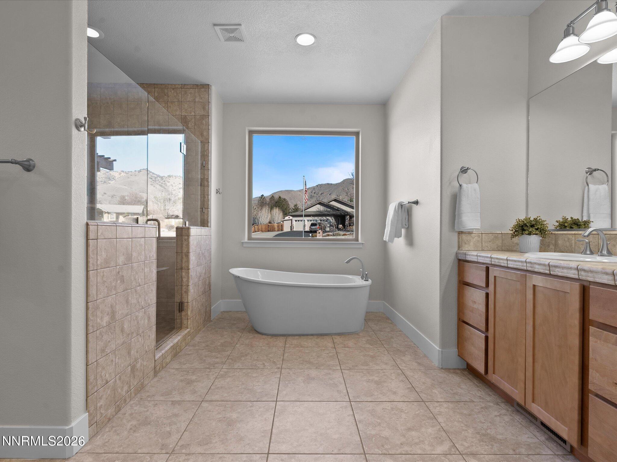 5585 East Hidden Valley Drive Reno, NV 89502 - Photo 19 of 40 a bathroom with a granite countertop sink a toilet a mirror and bathtub