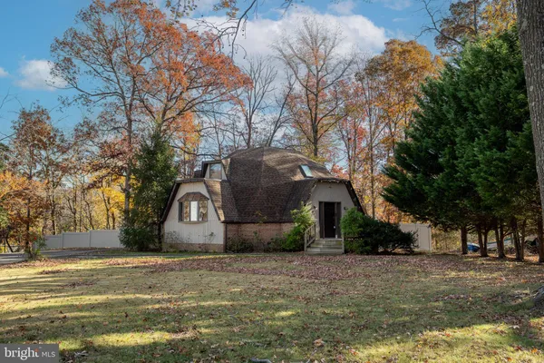 a front view of a house with a garden and trees