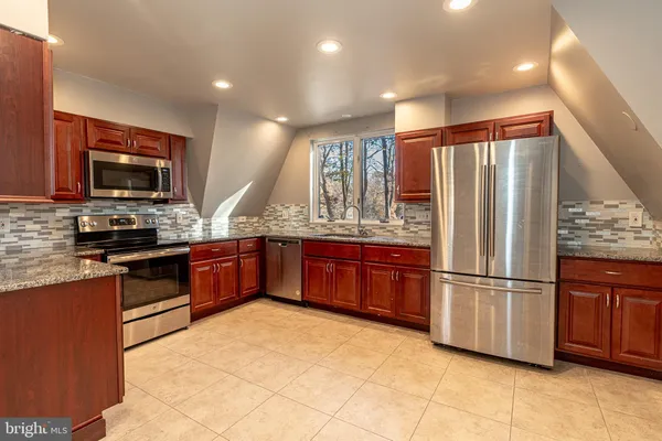 a kitchen with stainless steel appliances granite countertop a refrigerator a stove a sink and a microwave