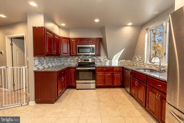 a large kitchen with stainless steel appliances granite countertop wooden cabinets a stove and a granite counter tops