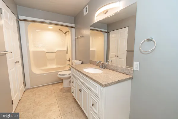 a bathroom with a granite countertop sink a toilet a mirror and a shower
