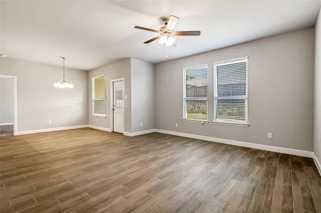 a view of an empty room with window and wooden floor