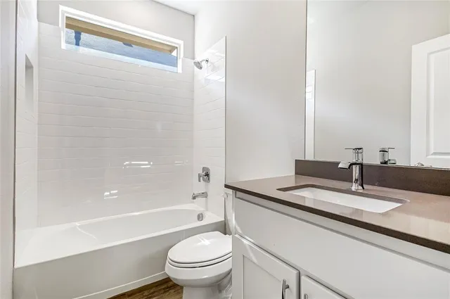 a bathroom with a granite countertop sink toilet mirror and bathtub