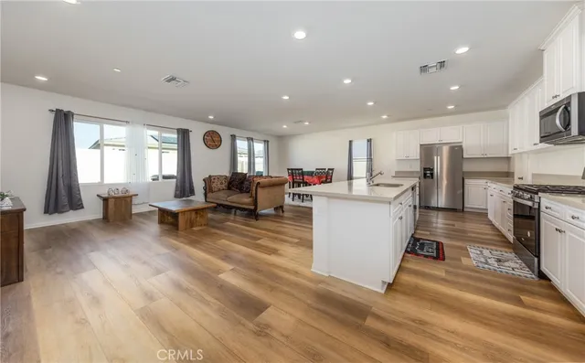 a living room with stainless steel appliances furniture a rug kitchen view and a chandelier