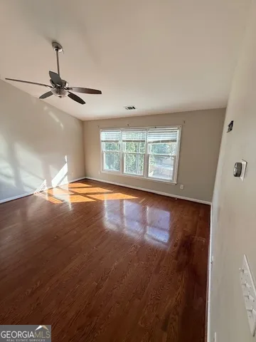 a view of empty room with wooden floor and fan