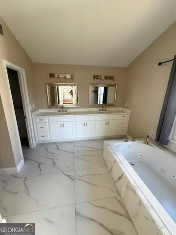 a spacious bathroom with a bathtub sink and mirror