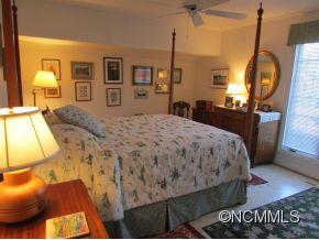 801 Golden Road Tryon, NC 28782 - Photo 14 of 24 a spacious bedroom with a bed a mirror on dresser and a wooden floor