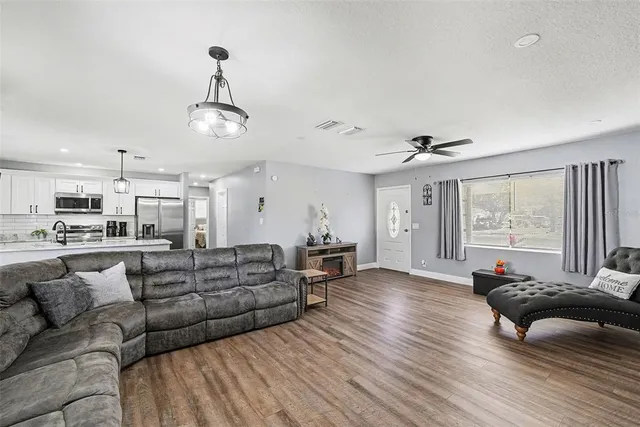 a living room with furniture kitchen view and a wooden floor