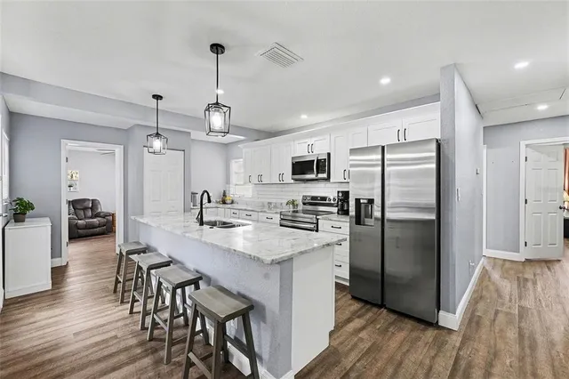 a kitchen with stainless steel appliances granite countertop a refrigerator a stove a sink dishwasher a dining table and chairs with wooden floor