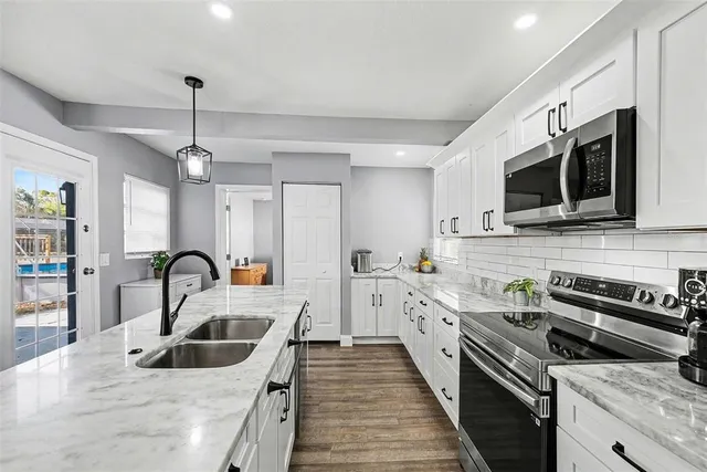 a kitchen with stainless steel appliances granite countertop a sink a stove top oven a counter space cabinets and stainless steel appliances