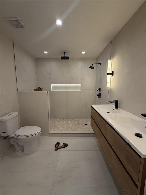 5021 Ashbrook Road Dallas, TX 75227 - Photo 9 of 12 Spacious bathroom featuring a floating wood-finish double vanity with integrated sinks, a walk-in shower with dual showerheads, and recessed lighting