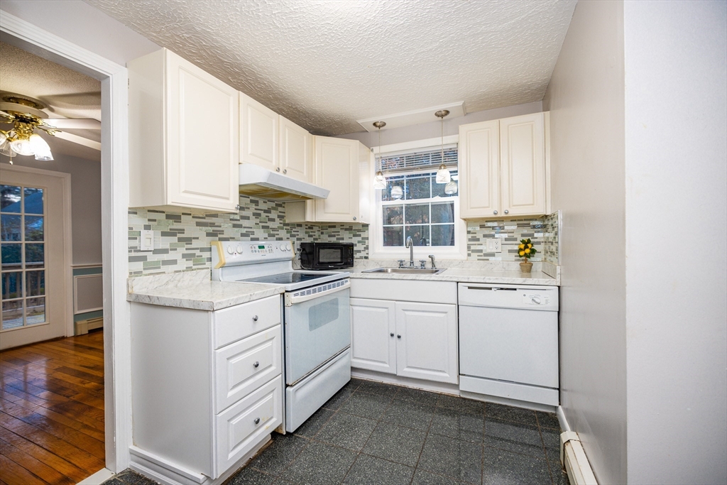 a kitchen with white cabinets appliances a sink and a window
