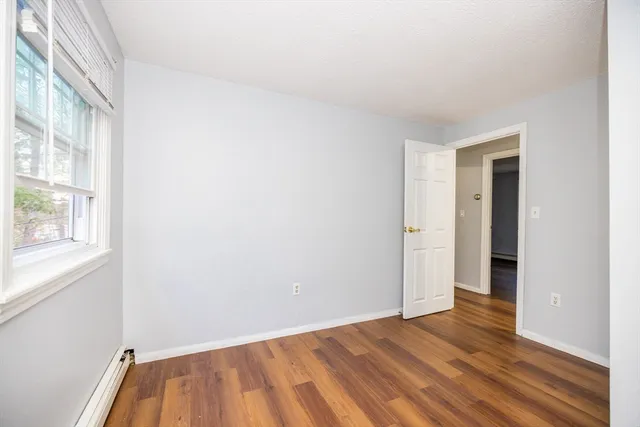 a view of an empty room with wooden floor and a window