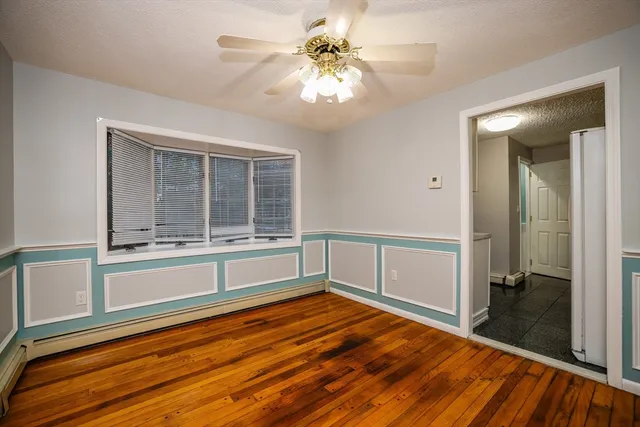 a view of an empty room with window and wooden floor
