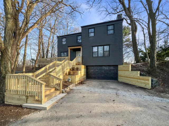a view of a house with a wooden bench next to a road