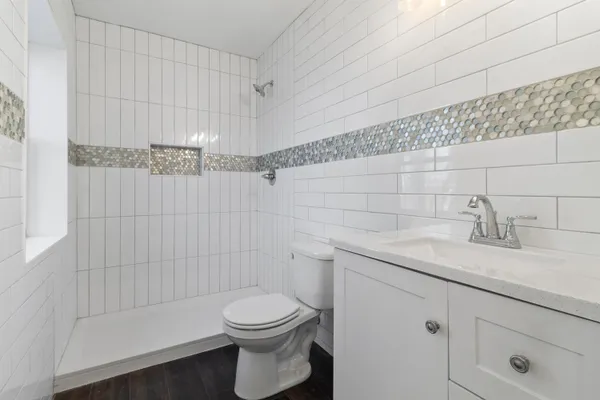 a bathroom with a granite countertop bathtub sink vanity mirror and toilet
