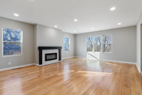 a view of empty room with wooden floor and fireplace