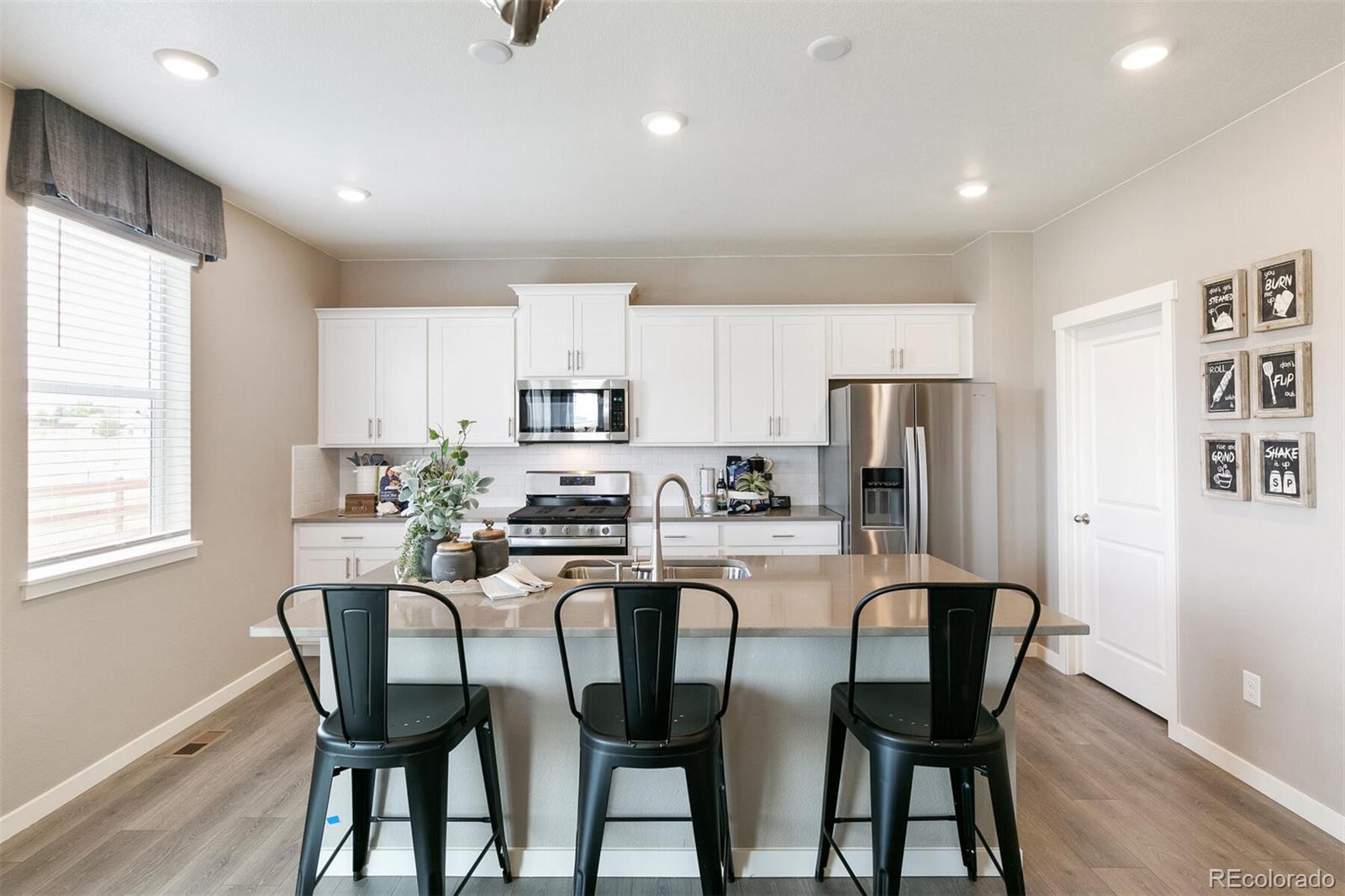 2238 Base Street Fort Lupton, CO 80621 - Photo 9 of 30 a kitchen with stainless steel appliances a dining table chairs refrigerator and microwave