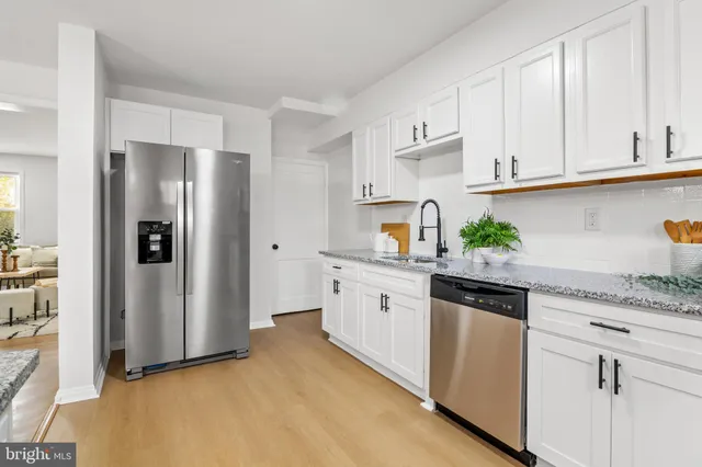 a kitchen with stainless steel appliances granite countertop white cabinets a refrigerator and a stove