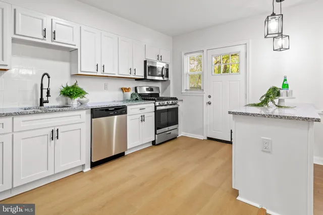 a kitchen with stainless steel appliances granite countertop white cabinets a stove top oven a sink and dishwasher