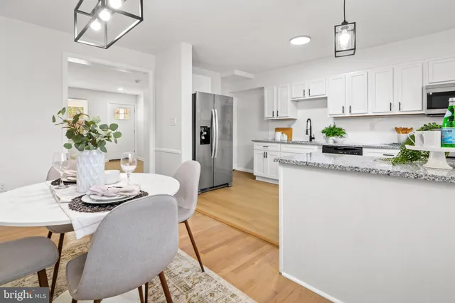 a kitchen with stainless steel appliances granite countertop a dining table chairs and white cabinets