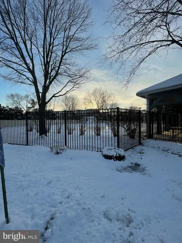 a view of a house with a wooden fence and large trees