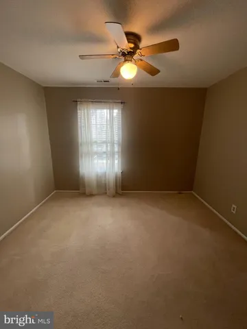 an empty room with a ceiling fan and window