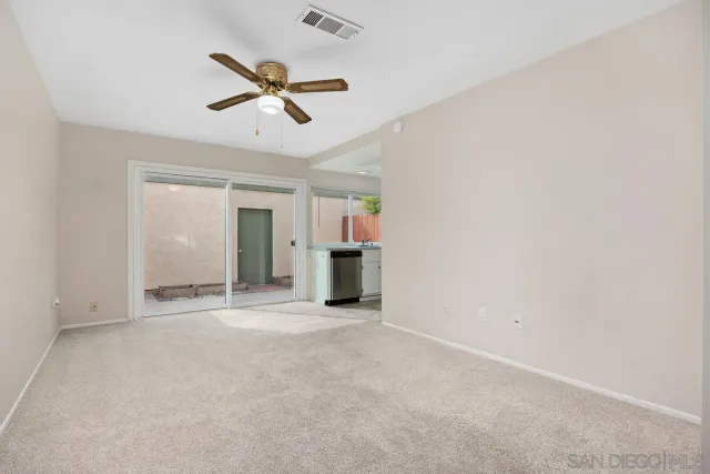 an empty room with ceiling fan and window