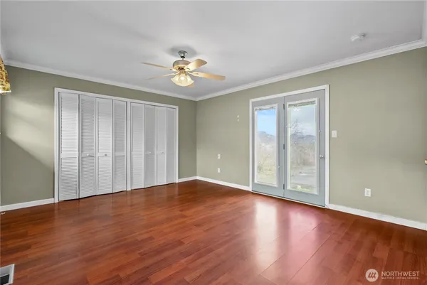 a view of an empty room with a window and wooden floor