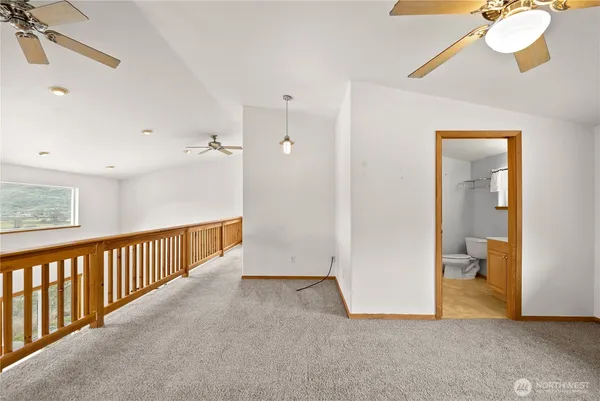 a view of a hallway with a dining room and chandelier fan