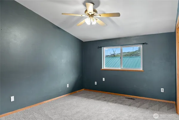 an empty room with windows and fan
