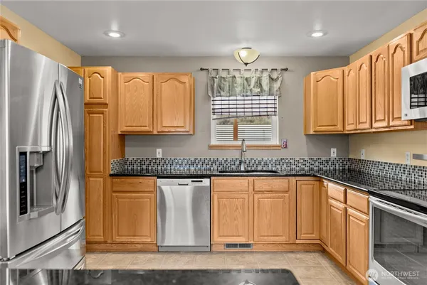 a kitchen with stainless steel appliances granite countertop a stove a sink and a refrigerator with wooden floor
