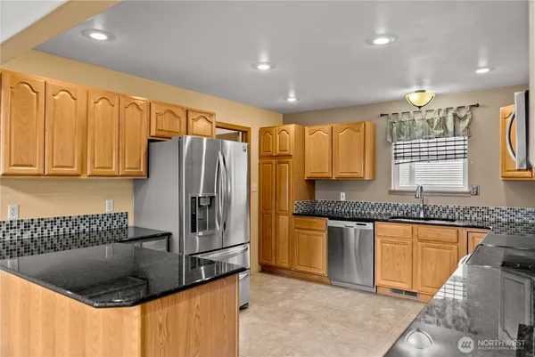 a kitchen with stainless steel appliances granite countertop a sink a stove and refrigerator