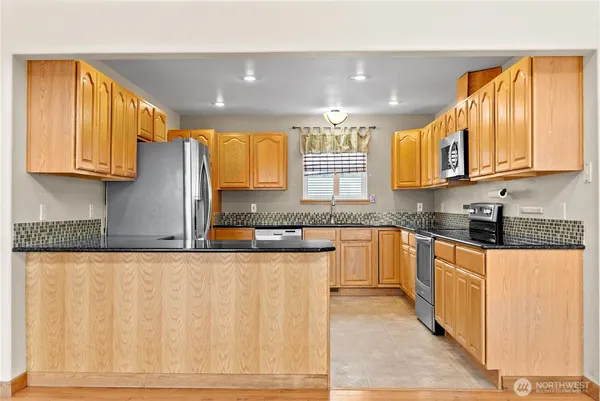 a kitchen with stainless steel appliances granite countertop a stove a sink and a microwave