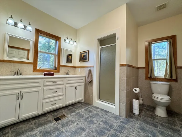 a spacious bathroom with a granite countertop toilet a sink and a large mirror