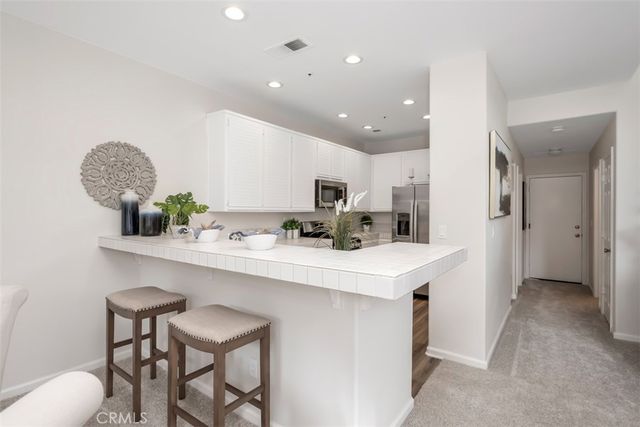 a kitchen with stainless steel appliances a sink a table and chairs in it