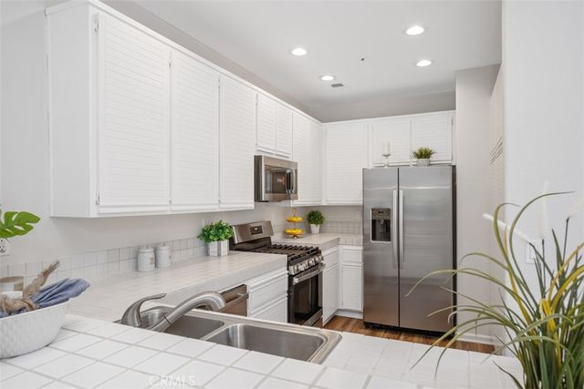 a kitchen with stainless steel appliances a refrigerator sink and white cabinets