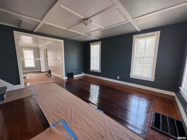 a view of an empty room with window and wooden floor