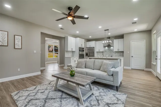 a living room with stainless steel appliances kitchen island granite countertop furniture and a rug