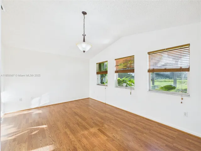 a view of empty room with wooden floor and window
