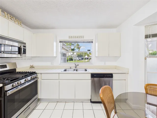 a kitchen with stainless steel appliances a stove a sink a refrigerator a stove a microwave and cabinets