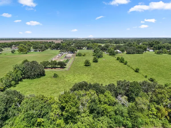 an aerial view of a houses with outdoor space and trees all around