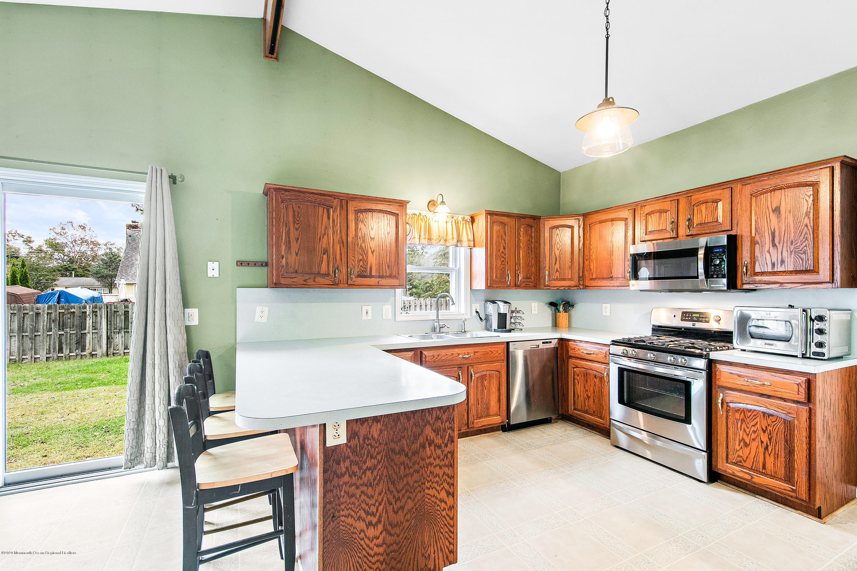 121 Wave Road Manahawkin, NJ 08050 - Photo 20 of 40 a kitchen with stainless steel appliances granite countertop a stove top oven a sink dishwasher a dining table and chairs with wooden floor
