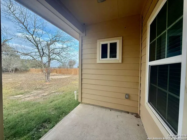 a view of an empty room and kitchen view with wooden floor