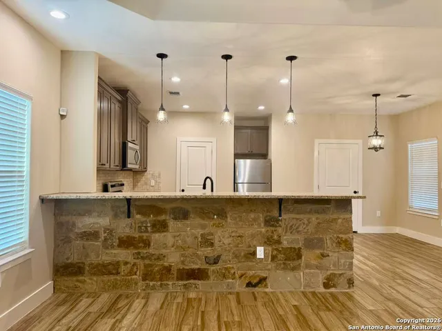 a view of a kitchen with wooden floor and a ceiling fan