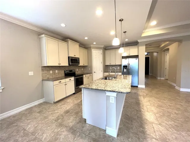 a kitchen with stainless steel appliances granite countertop a stove top oven a sink a refrigerator and white cabinets